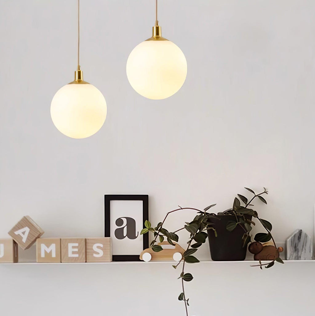 A shelf of wood letter blocks sits beneath two brass-and-white Clérachic sphere pendants at staggered heights.
