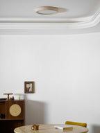 Unlit in the corner of a room with cornice moulding, this Clérachic ceiling light sits above a cane cabinet and a set table.