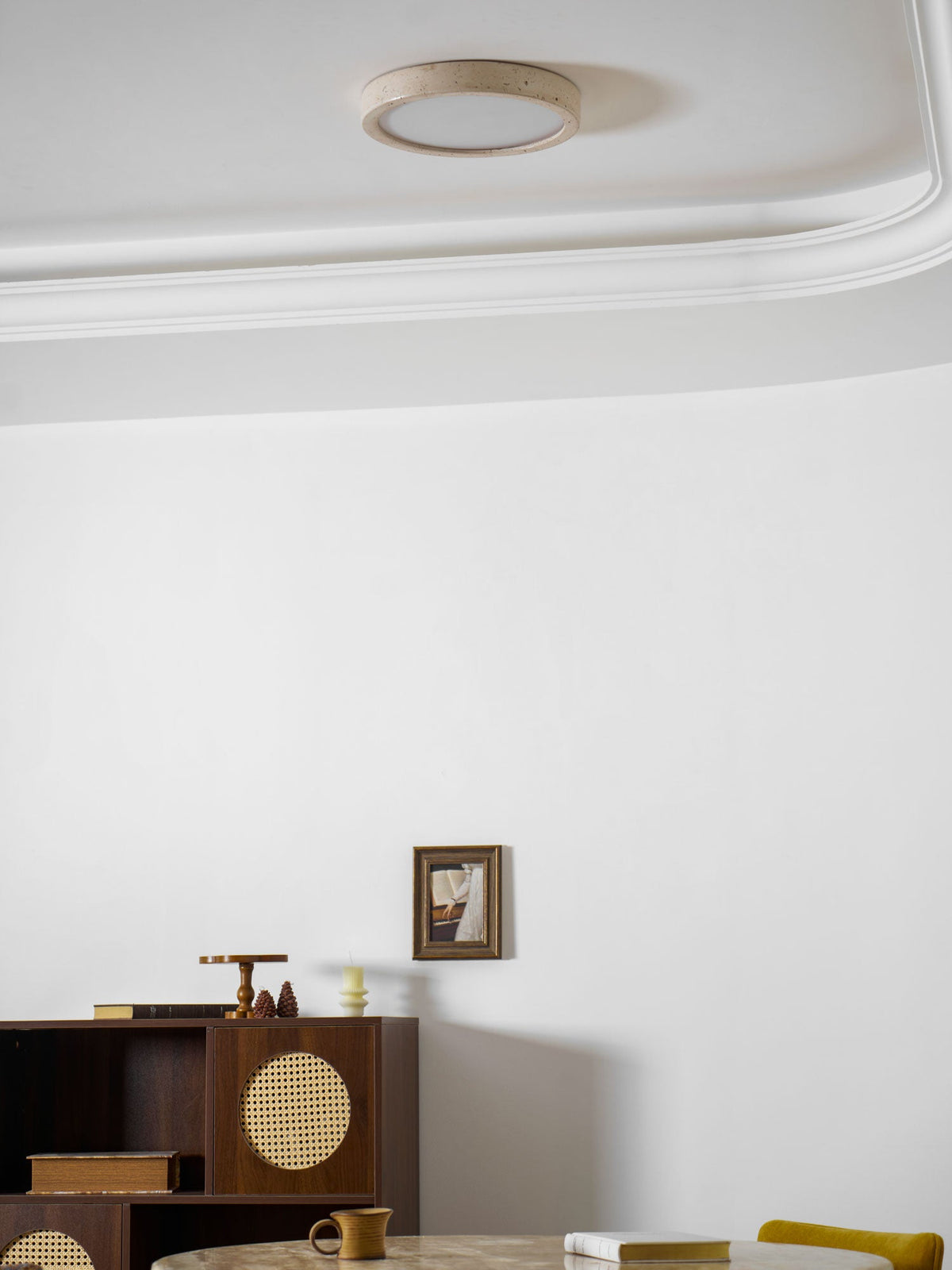 Glowing warmly by the cornice, this Clérachic ceiling light lights the same dining corner with its cane cabinet.