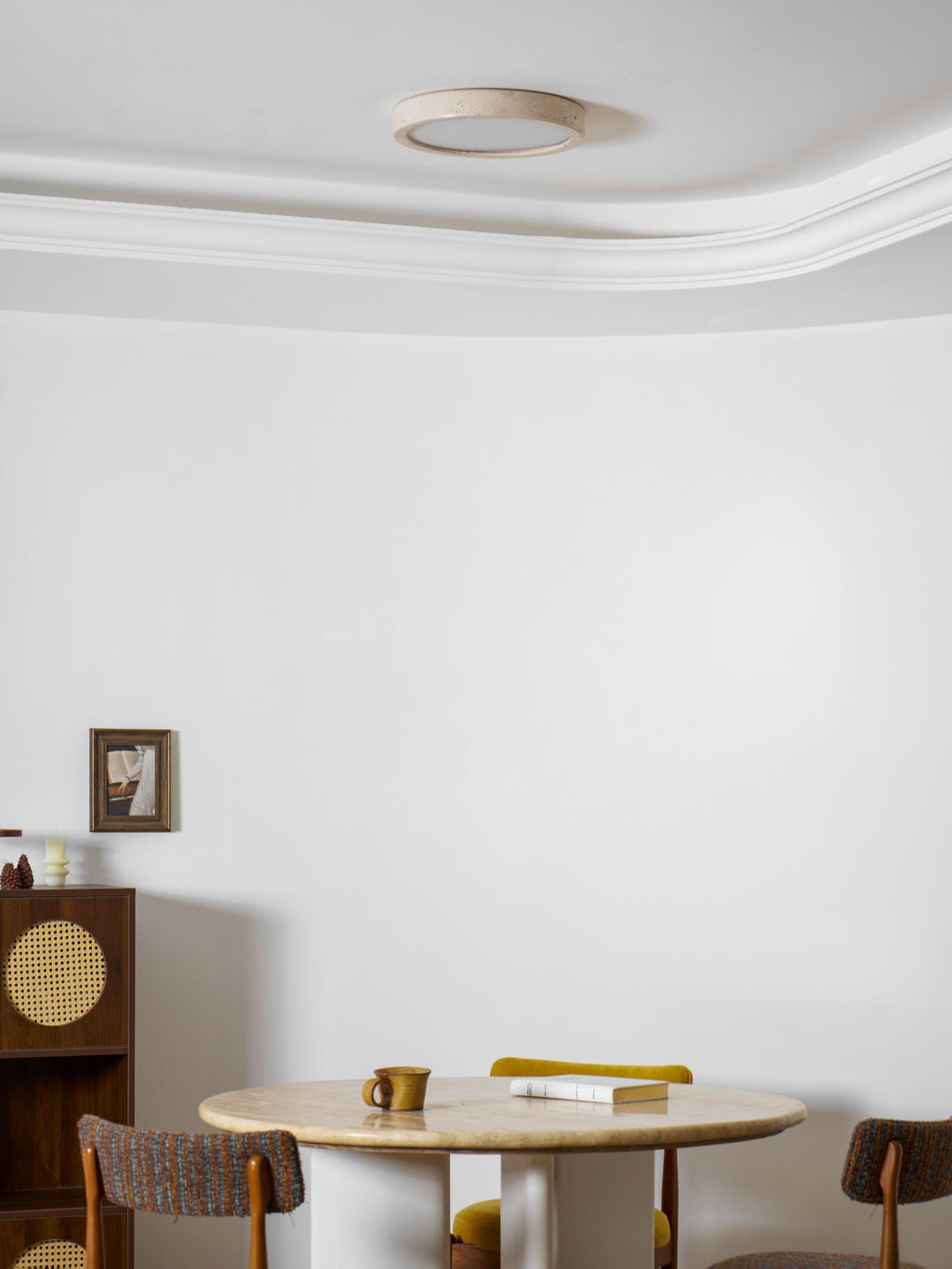 Unlit, this Clérachic ceiling light sits above a full view of the dining corner with mismatched wood and rush chairs.
