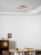 Seen close to the cornice, this Clérachic ceiling light is unlit above the cane cabinet and round travertine table.
