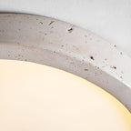 Close view of the travertine ring on this Clérachic ceiling light, lit warmly to show its natural veining and pitting.