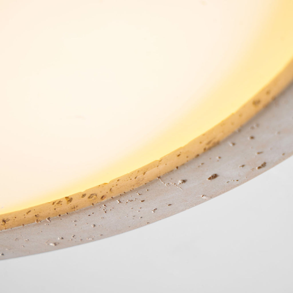 Extreme close-up of the travertine ring on this Clérachic ceiling light, lit warmly to show the stone's texture.