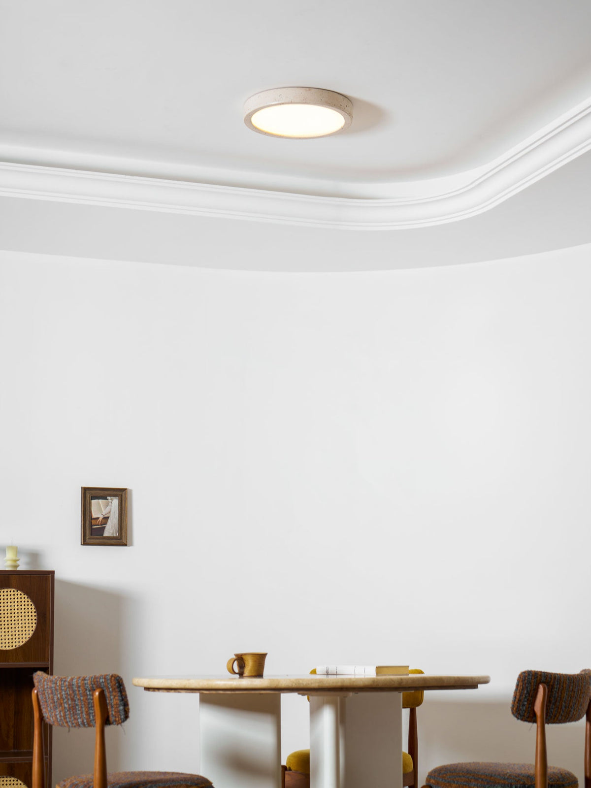 A wider angle shows this Clérachic ceiling light glowing warmly above the cane cabinet and dining chairs.