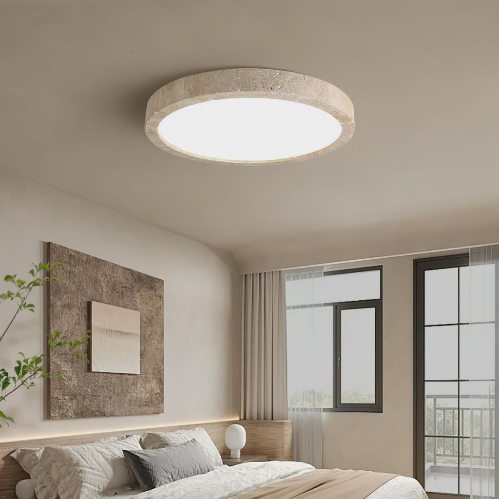 Mounted above a bed with a framed abstract print, this Clérachic ceiling light shows its travertine ring and white centre panel.