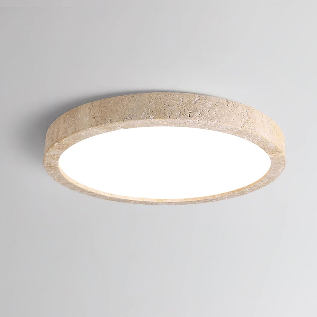 A closer angle shows the travertine ring and white centre of this Clérachic ceiling light against plain grey.