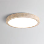 A closer angle shows the travertine ring and white centre of this Clérachic ceiling light against plain grey.
