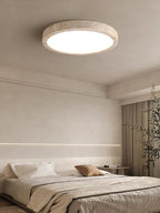 In a bedroom with a cove-lit alcove and a potted plant, this Clérachic ceiling light is mounted flush overhead.