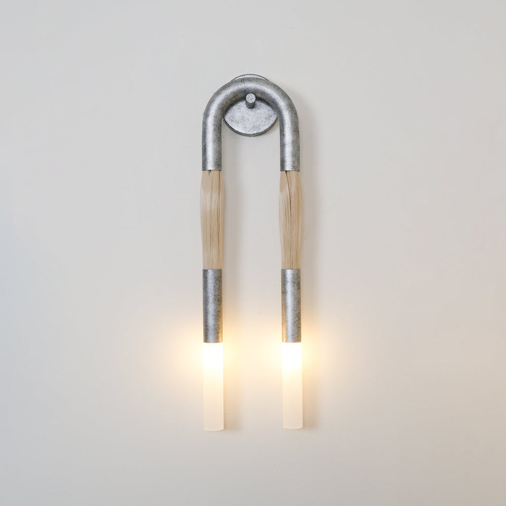 Wrought-iron wall lamp shaped like a horse mane glowing warm
