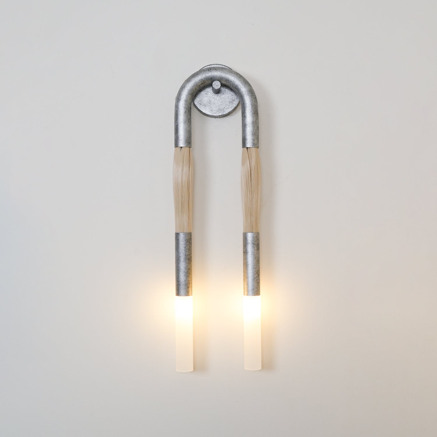 Wrought-iron wall lamp shaped like a horse mane glowing warm