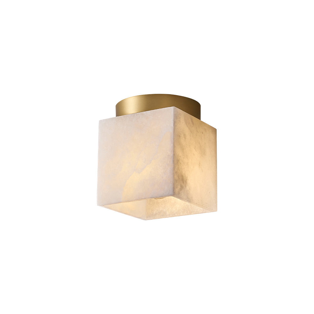 The Usilia alabaster ceiling light on a plain white background, warm honey-toned stone cube under a brass canopy.