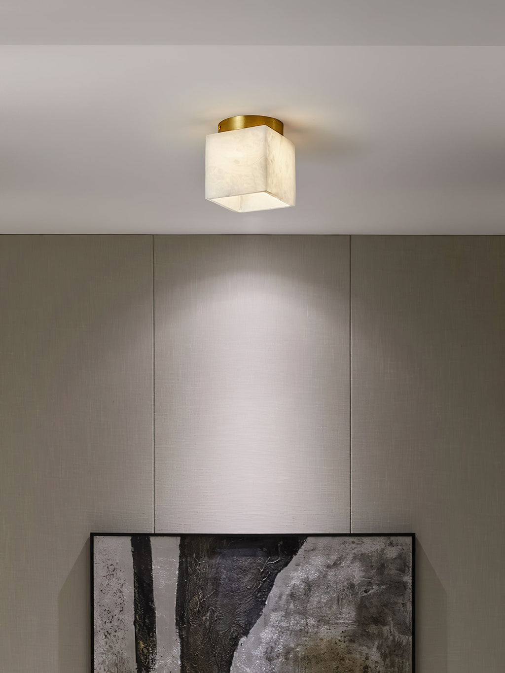 Usilia alabaster ceiling light lit above a linen-panelled wall, casting a soft pool of light down the wall.