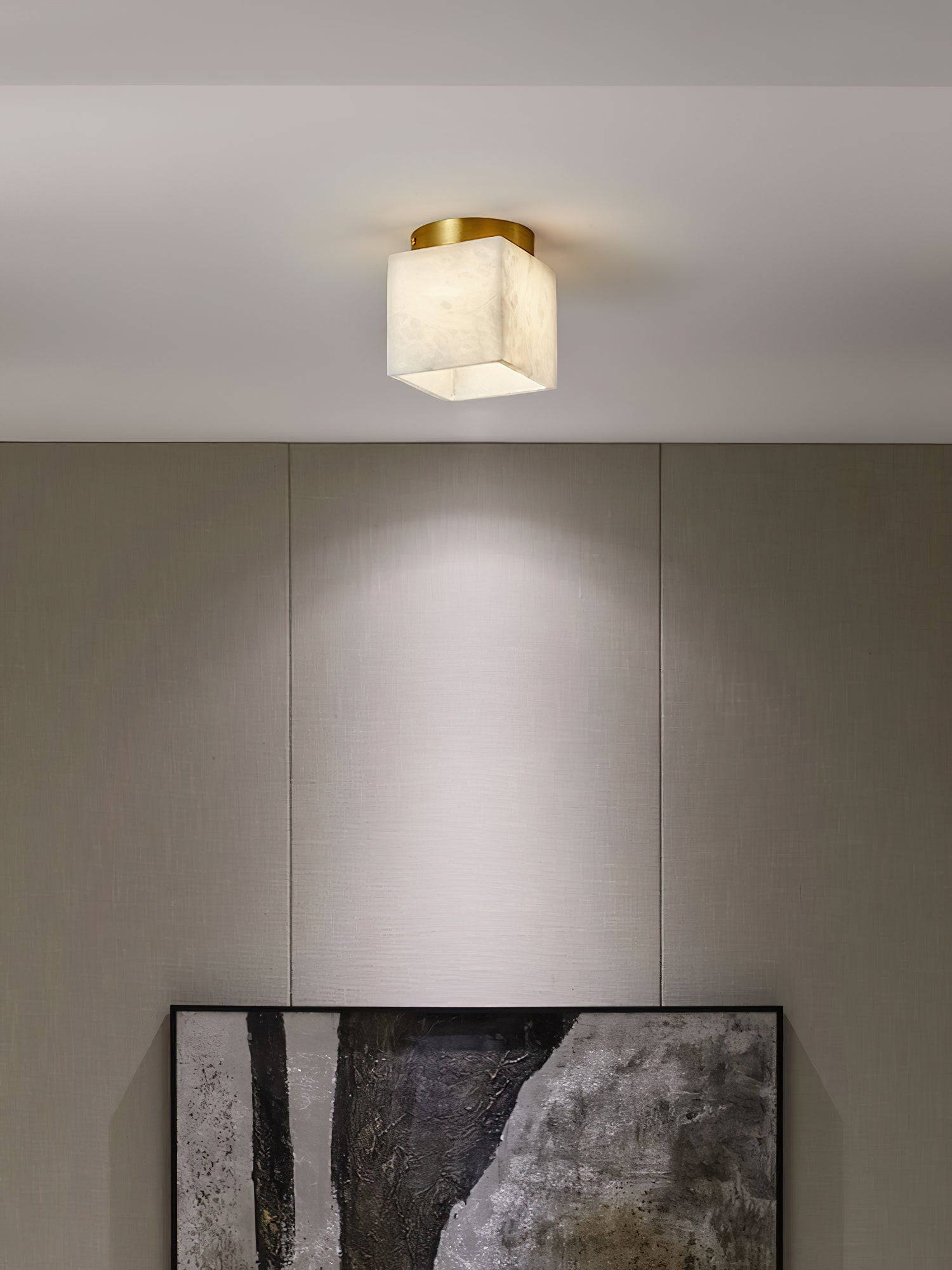 Usilia alabaster ceiling light lit above a linen-panelled wall, casting a soft pool of light down the wall.