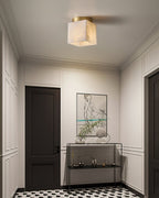 Usilia alabaster ceiling light glowing in a panelled entryway with a dark door and patterned tile floor.