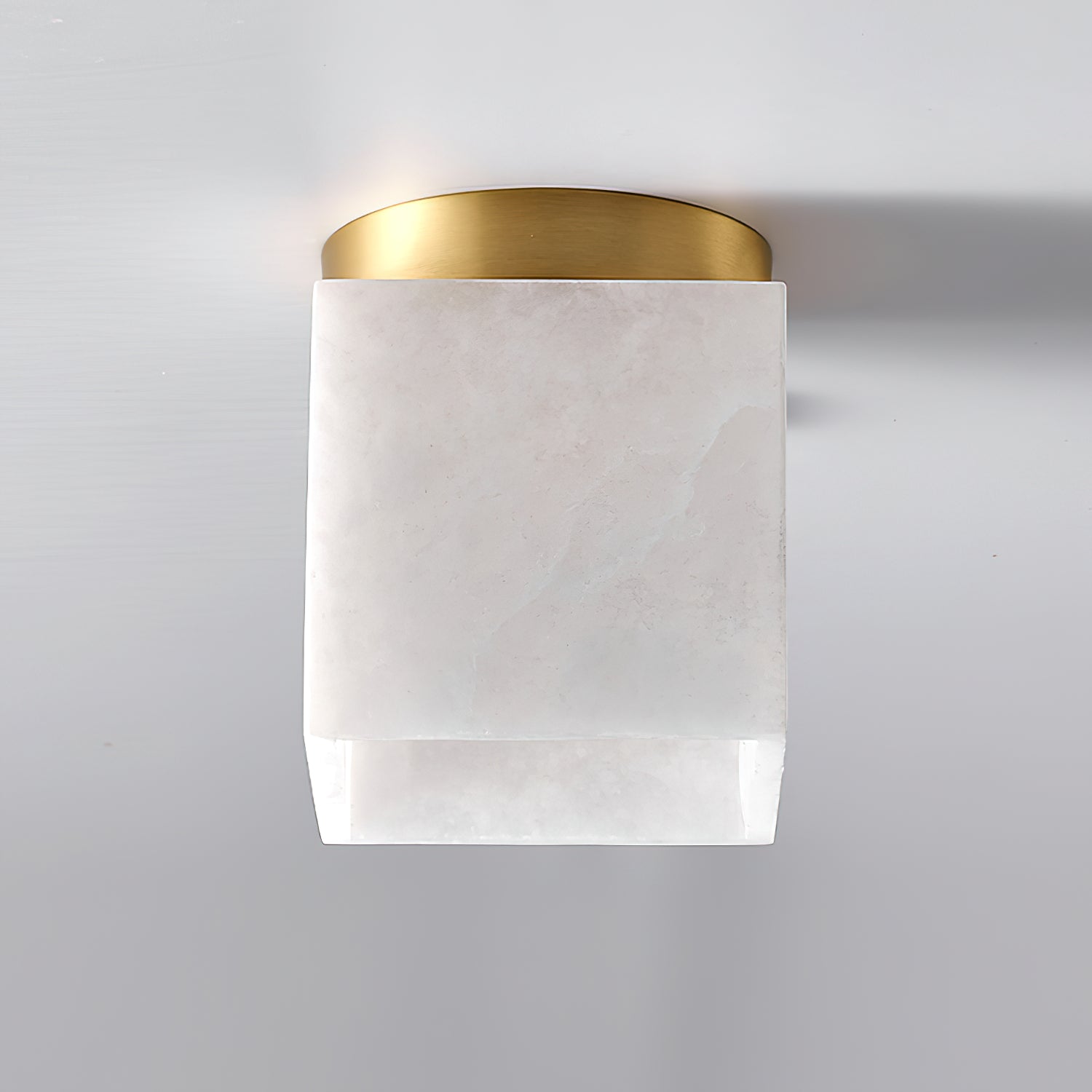 Straight-on view of the Usilia ceiling light, unlit, the round brass canopy above the square alabaster shade.