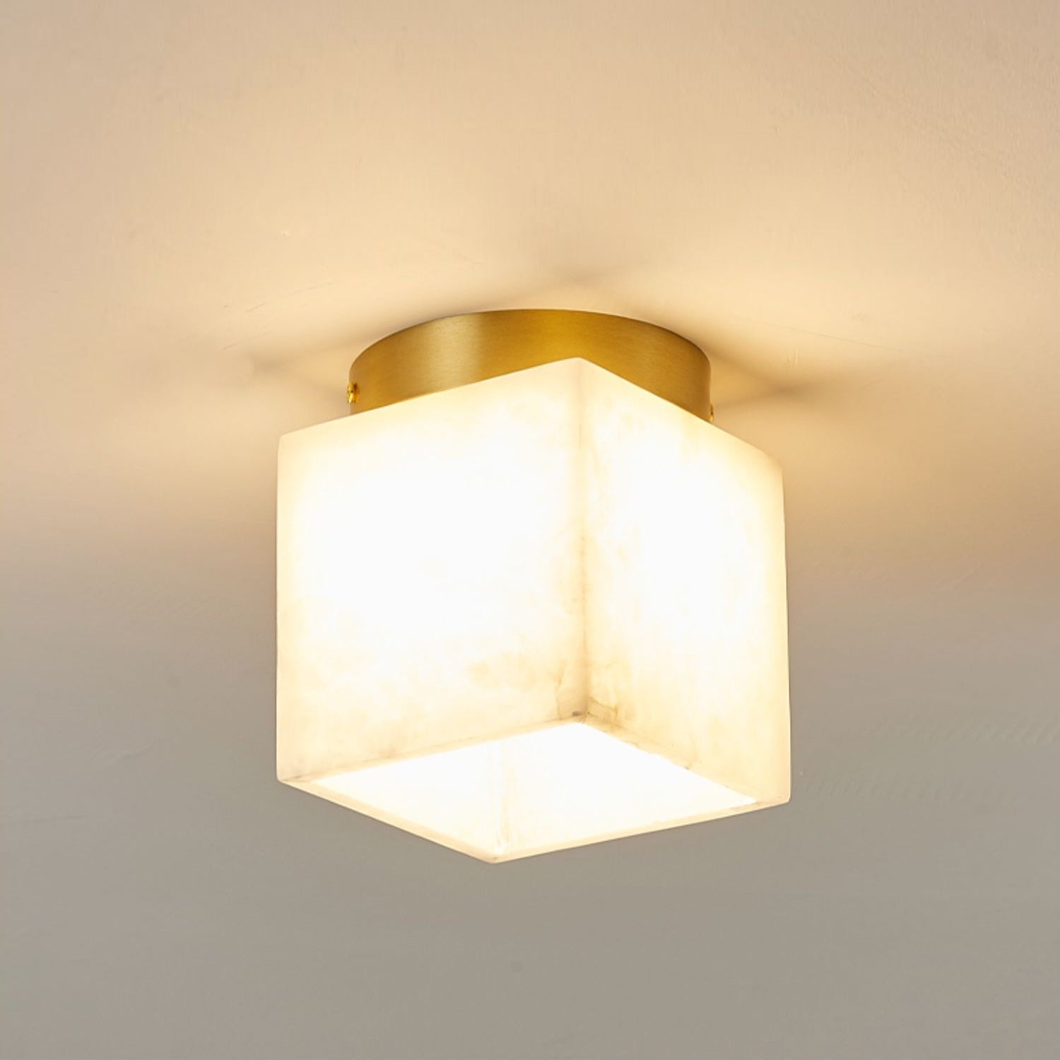 Usilia alabaster ceiling light at full brightness, the stone cube glowing warm white and washing the ceiling.