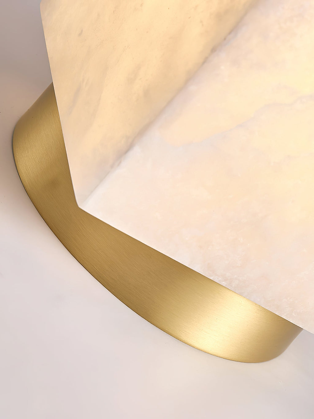 Macro detail of the brushed brass canopy meeting the corner of the Usilia light's alabaster shade.