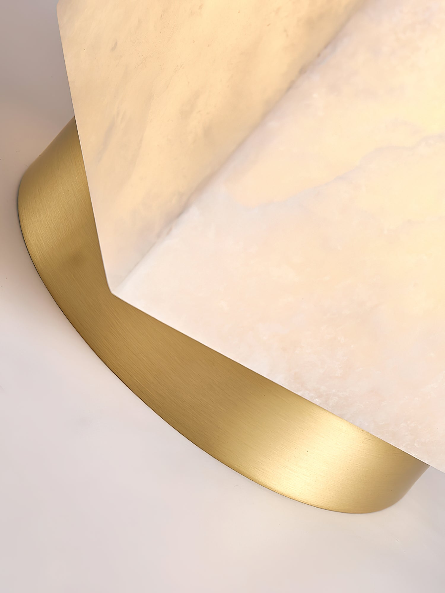Macro detail of the brushed brass canopy meeting the corner of the Usilia light's alabaster shade.
