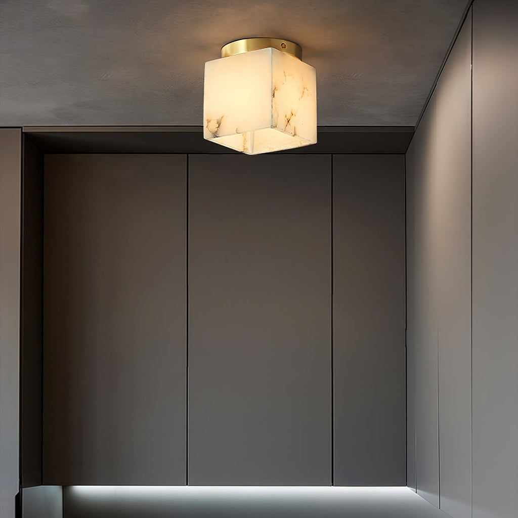 Usilia alabaster ceiling light lit on a dark grey ceiling, heavy stone veining clear above tall grey cabinetry.