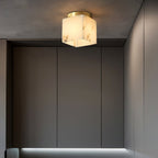 Usilia alabaster ceiling light lit on a dark grey ceiling, heavy stone veining clear above tall grey cabinetry.