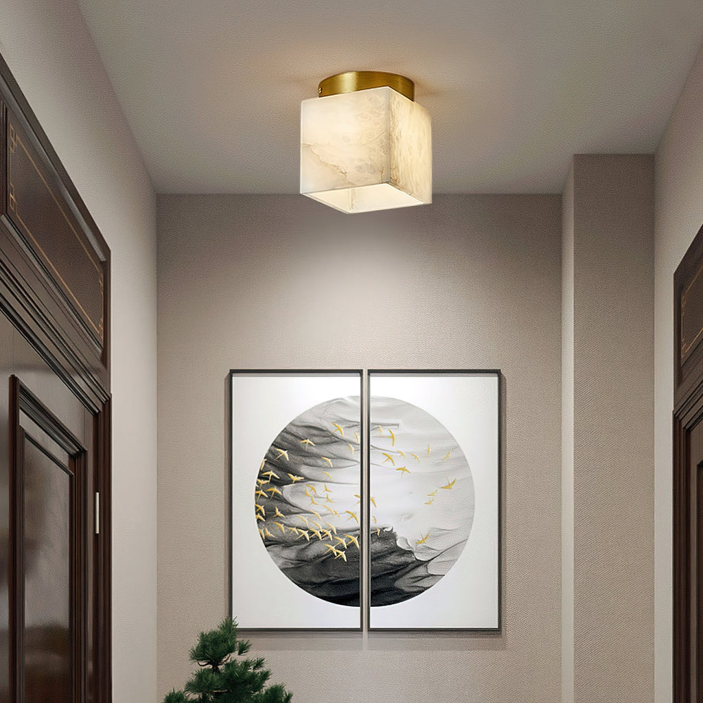 Usilia alabaster ceiling light lit in a hallway above a framed pair of bird prints, dark wood cabinets either side.