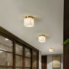 Three Usilia alabaster ceiling lights lit in a row along a corridor beside a wood-framed glass partition.