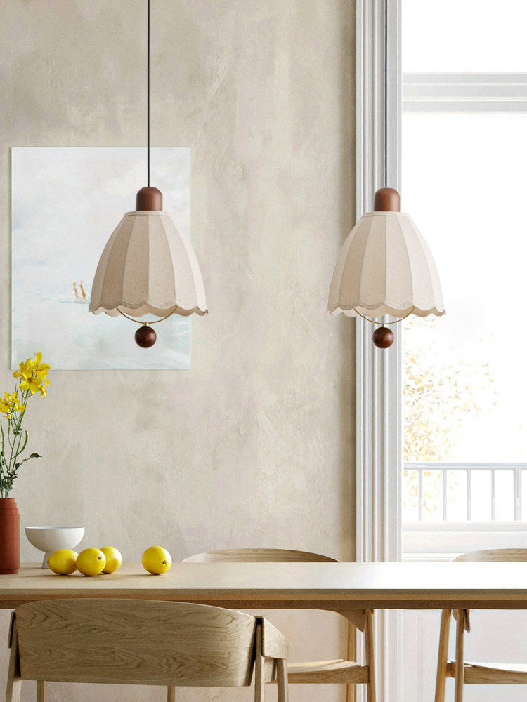 Side by side near a plaster wall, two of these Clérachic pendants hang above flowers and lemons on the table.