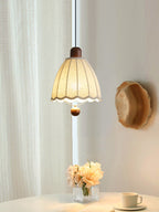 Beside a sheer curtain, this Clérachic pendant hangs above a small table with fresh flowers and a cup.