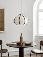 This Clérachic pendant's tapering shade glows warm above a round table set with a bottle and small plates.