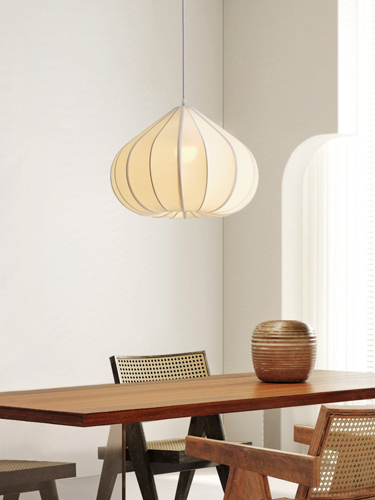 This Clérachic pendant's tapering fabric shade glows warm above a wood dining table flanked by cane-backed chairs.