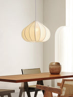 This Clérachic pendant's tapering fabric shade glows warm above a wood dining table flanked by cane-backed chairs.