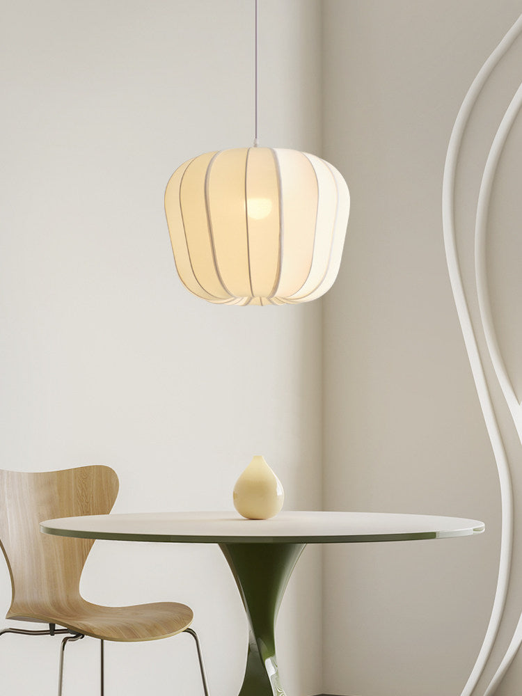 This Clérachic pendant's rounded shade, ribbed with black seam trim, glows warm in a room corner beside a round table.