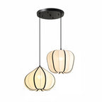Two Clérachic pendant shades, one tapering and one rounded, hang at different heights from a shared black canopy, both glowing warm.