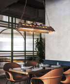 Linear industrial chandelier in rust finish with warm amber glow