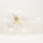 Multi-arm ceiling light with brass body and white oval glass shades