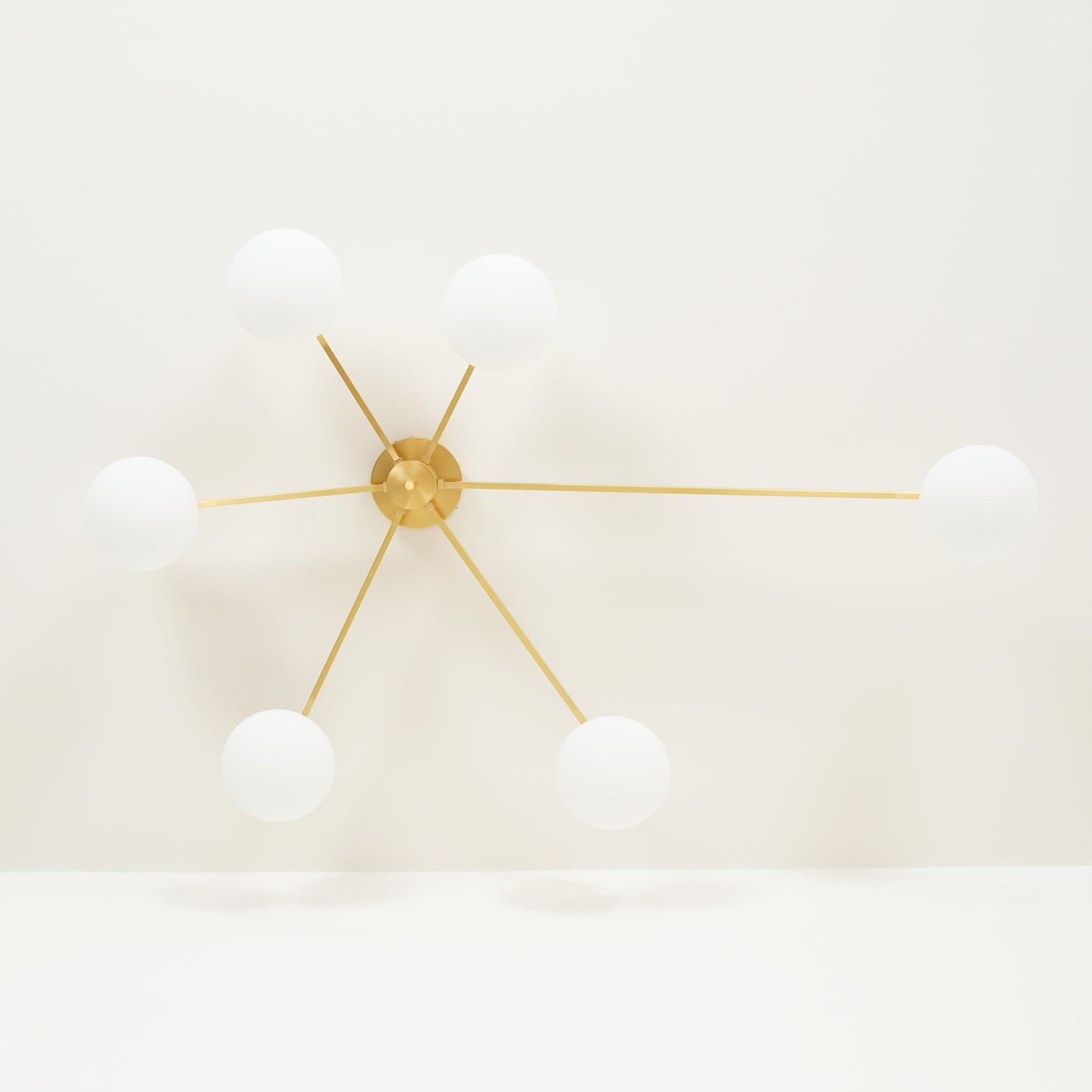 Multi-arm ceiling light with brass body and white oval glass shades