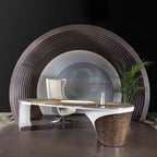On an office desk inside an arched alcove, the Clérachic table lamp's marble base and LED bar sit beside a white chair and potted plant.