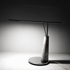 Clérachic table lamp photographed alone on a grey studio backdrop, showing the full marble cone base and slim horizontal LED bar.