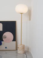 A tighter crop of the Clérachic floor lamp in a white corner, its frosted globe beside a leaning abstract print.