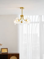 Another view beside a sheer curtain shows this Clérachic chandelier's brass arms spread with ruffled glass shades.