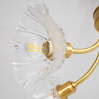 Another close view shows a lit glass petal shade on this Clérachic chandelier, its fluted edge and brass arm in sharp detail.