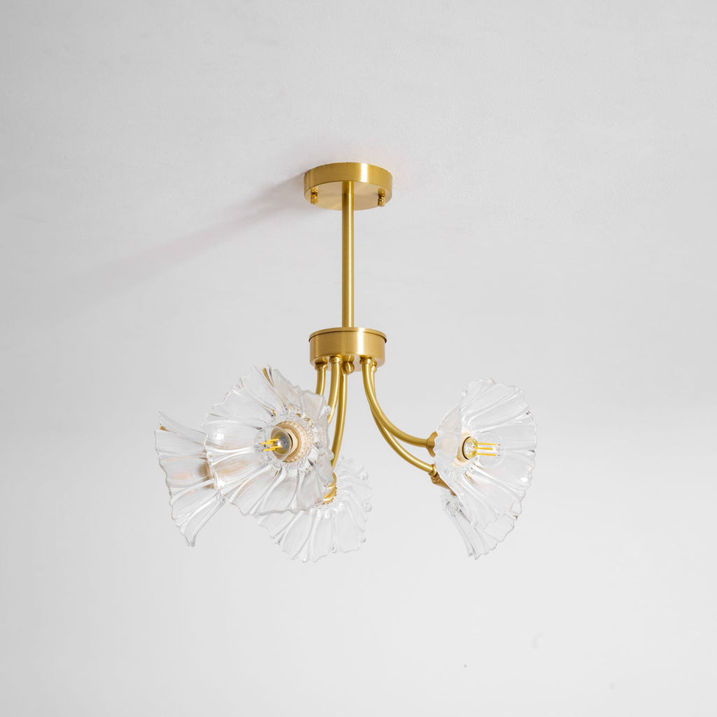 Another angle on a white backdrop shows this Clérachic chandelier's brass arms holding ruffled glass petal shades close together.