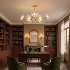 Bookshelves and a mirrored mantel frame this Clérachic chandelier in a wood-panelled study with a green leather chair.