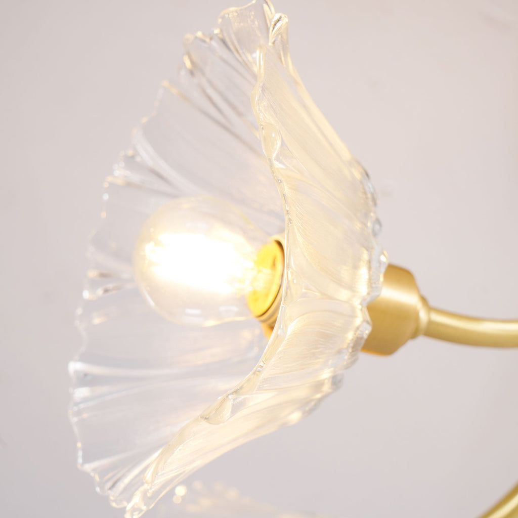 Close view of one lit clear glass petal shade on this Clérachic chandelier, its ribbed texture catching the warm bulb glow.
