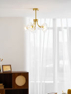 A rattan cabinet and a framed photo sit near a sheer curtain beneath this Clérachic chandelier.