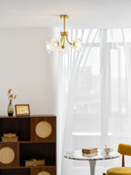 A rattan cabinet, a round marble table and a mustard chair sit in a room hung with this Clérachic chandelier.