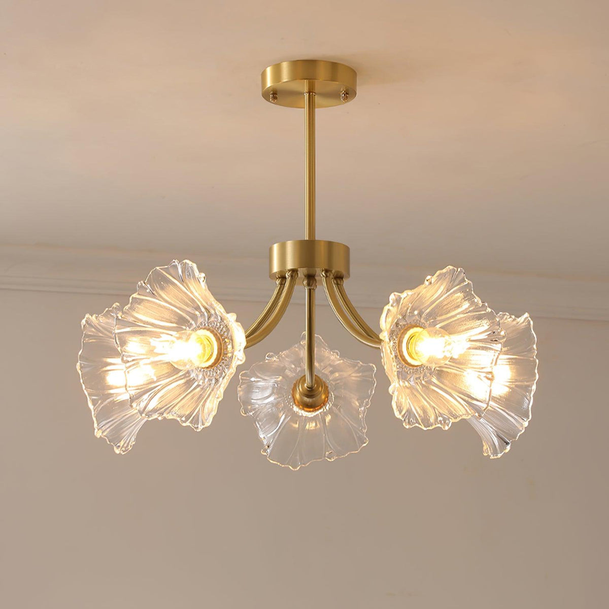 A closer angle against a grey wall shows three of this Clérachic chandelier's ruffled glass petal shades lit softly.
