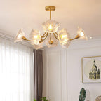 A black-framed picture on a plain grey wall sits beside this Clérachic chandelier, its brass arms catching the light.
