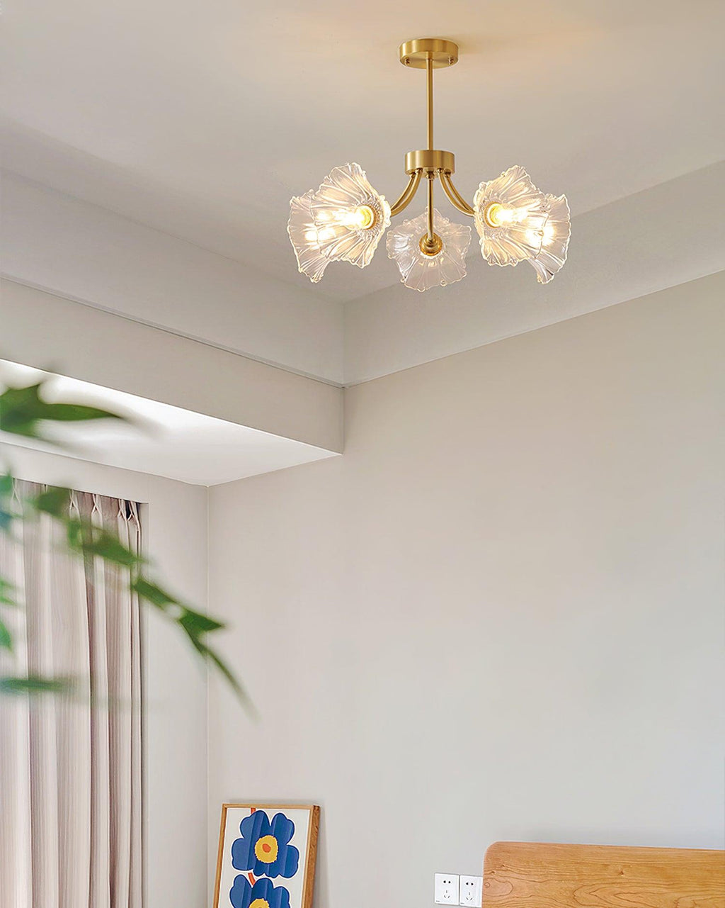 A potted plant and a yellow abstract artwork sit in the corner of a room hung with this Clérachic chandelier.