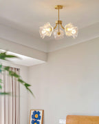 A potted plant and a yellow abstract artwork sit in the corner of a room hung with this Clérachic chandelier.